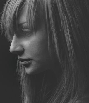 Artistic monochrome side portrait of a woman in studio lighting.