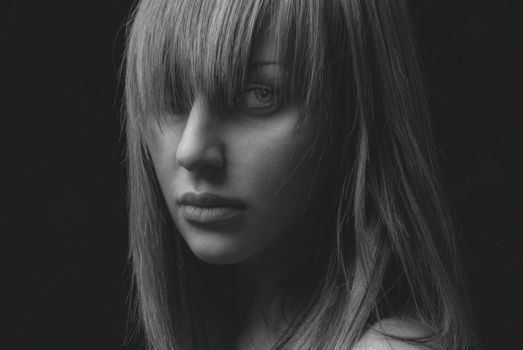 Black and white portrait of a woman with bangs gazing intently, highlighting emotions.