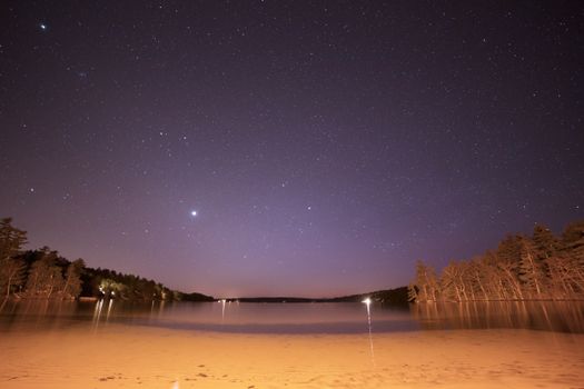 星空下，海滩夜色宁静，波光粼粼，远处树木轮廓依稀可见