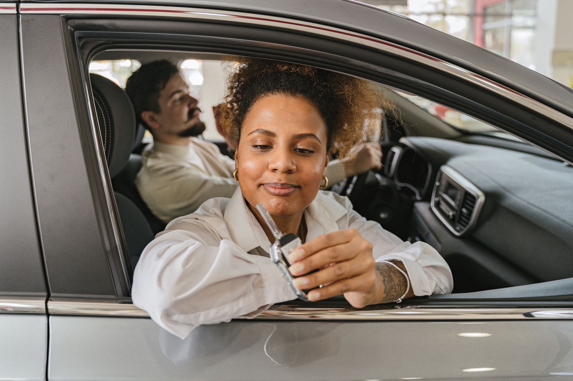 A man and woman in a car, showing car keys, symbolizing freedom and driving adventure.