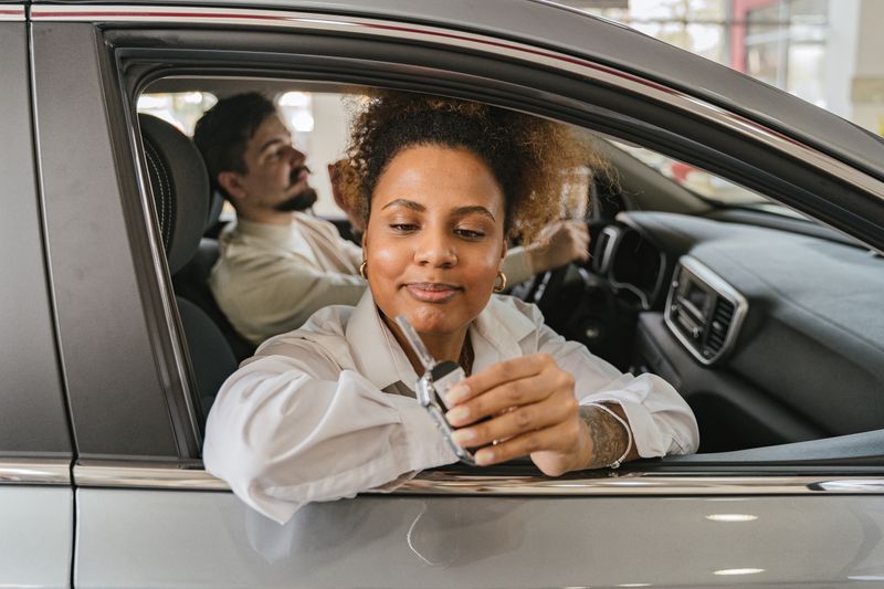 A man and woman in a car, showing car keys, symbolizing freedom and driving adventure.