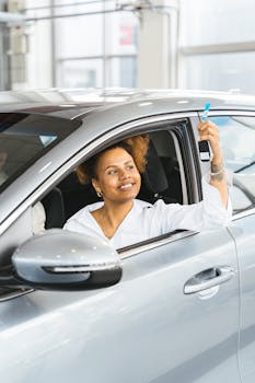Smiling woman holding car keys from driver's seat in a new car