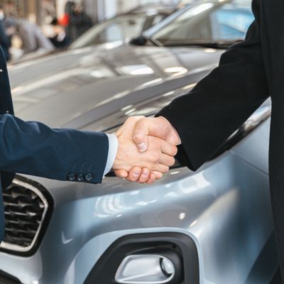 Two people shaking hands over a car deal