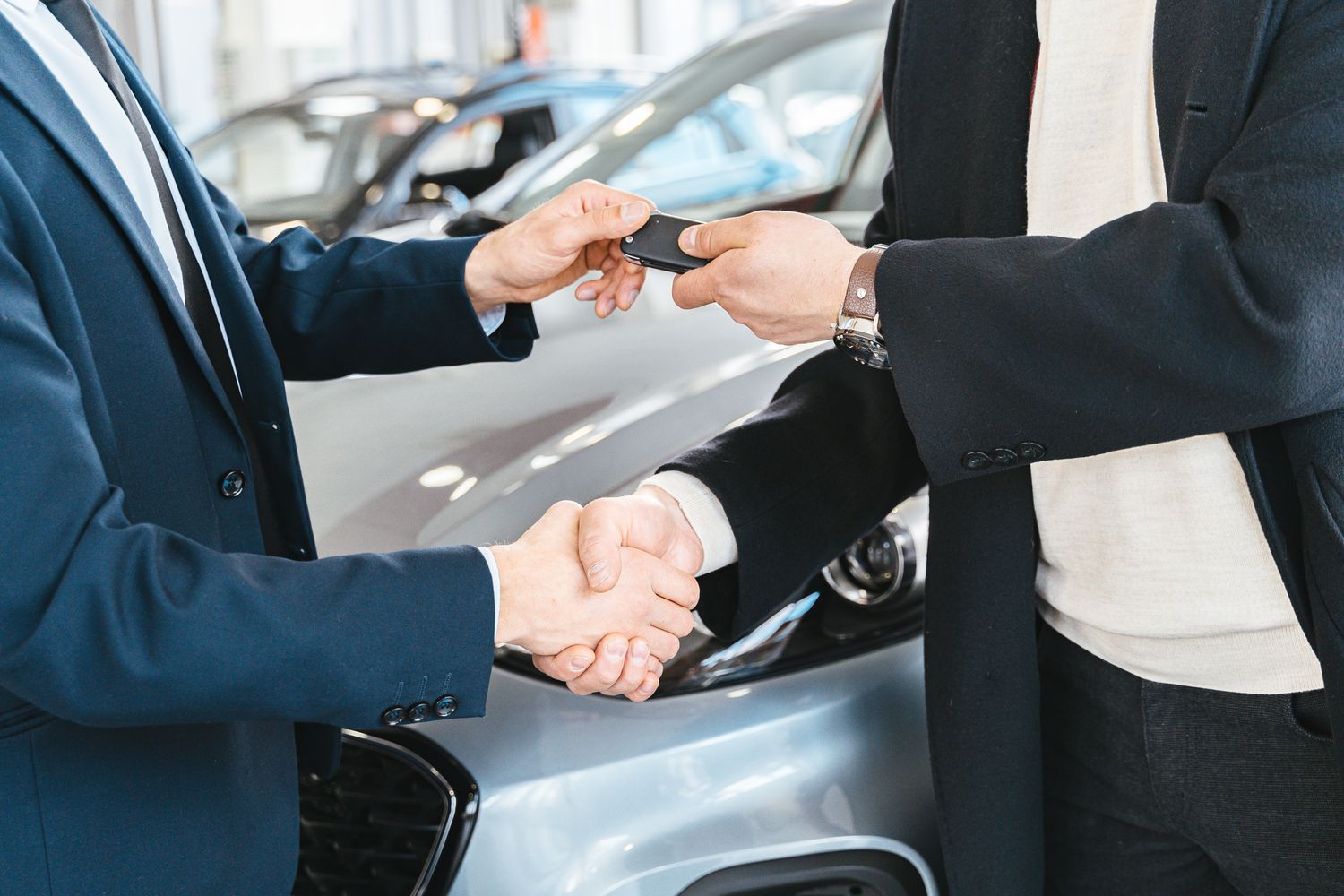 Salesperson handing keys to a happy customer at the dealership