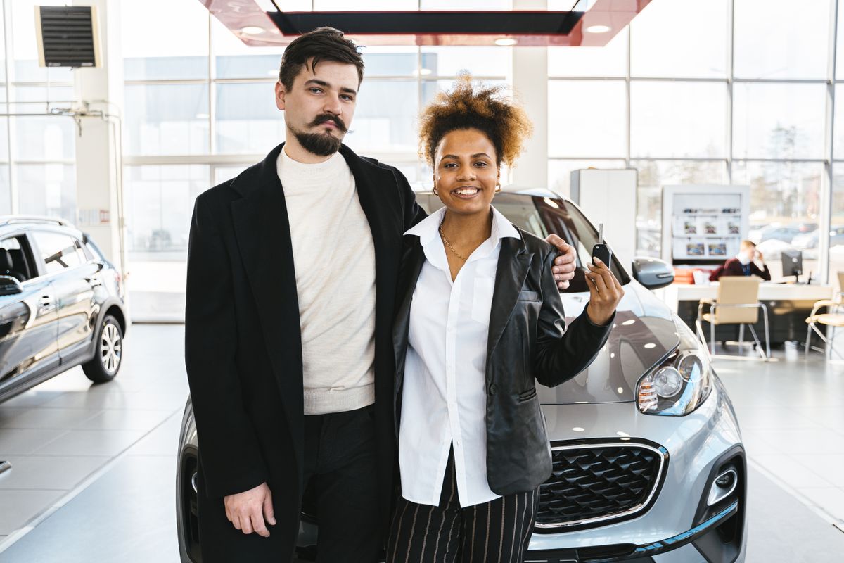 A couple looking over a used vehicle on a dealership lot