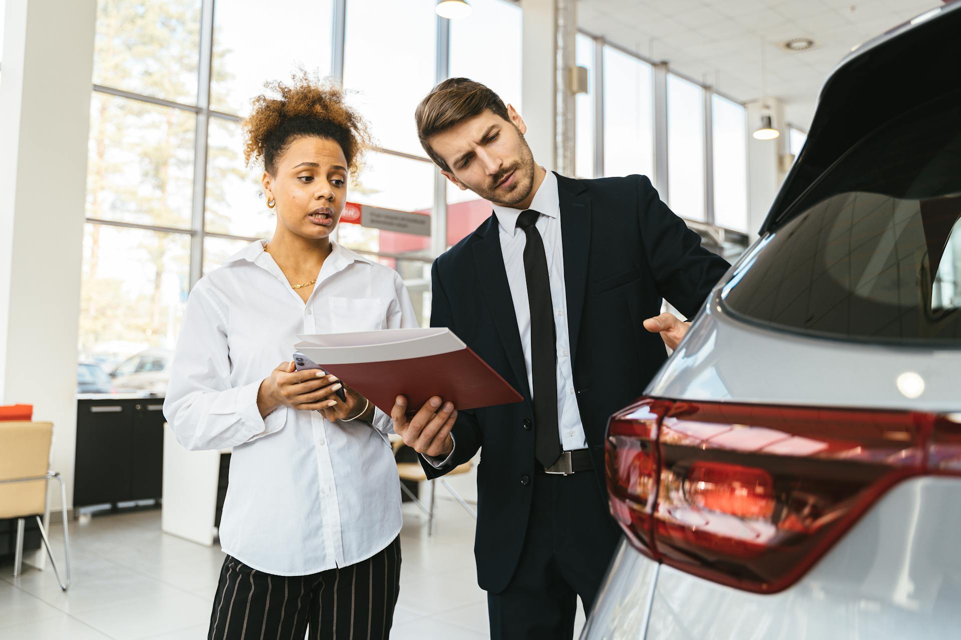 A professional consultation at a car dealership involving a sales agent and a customer discussing a vehicle purchase.