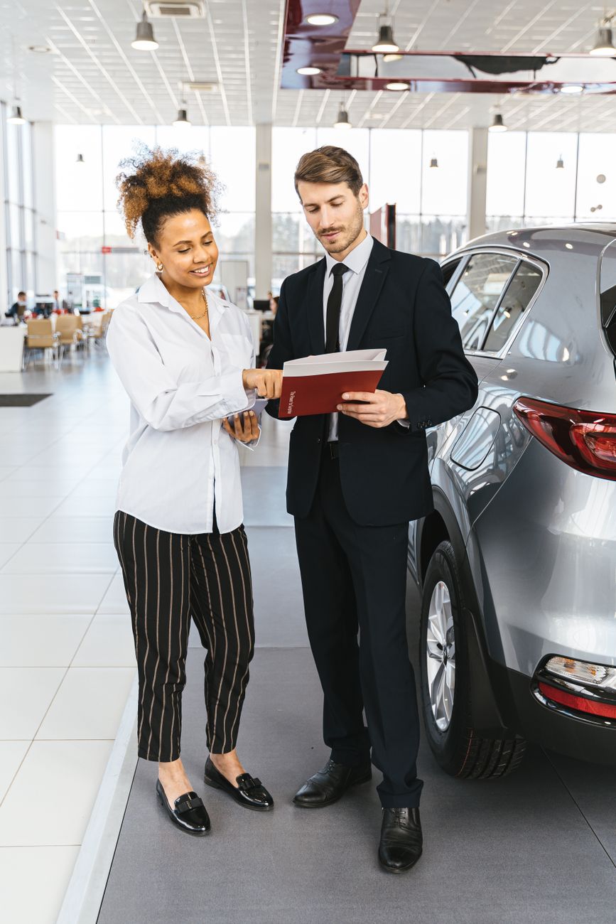 Man and woman discussing car purchase inside a modern dealership