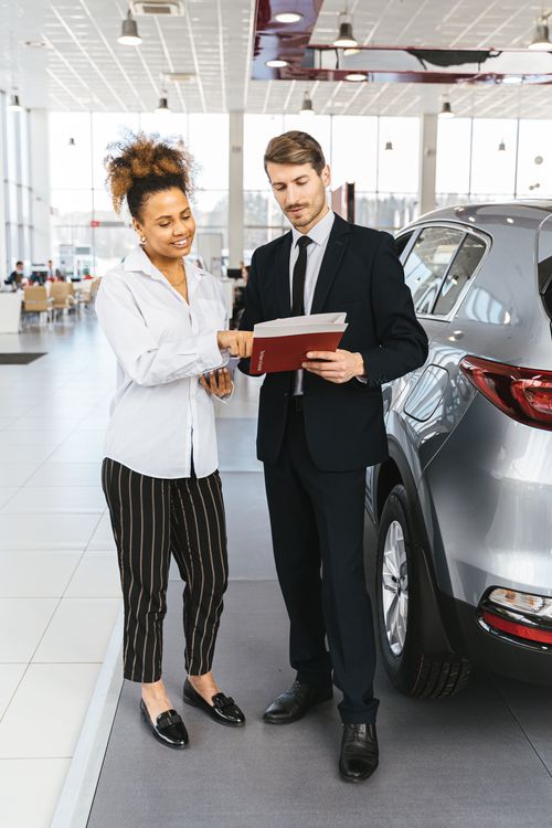 Free Man and woman discussing car purchase inside a modern dealership. Stock Photo