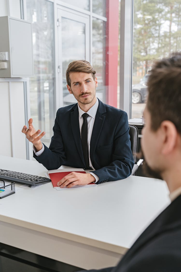 Man Sitting At Desk In Office Consulting Client