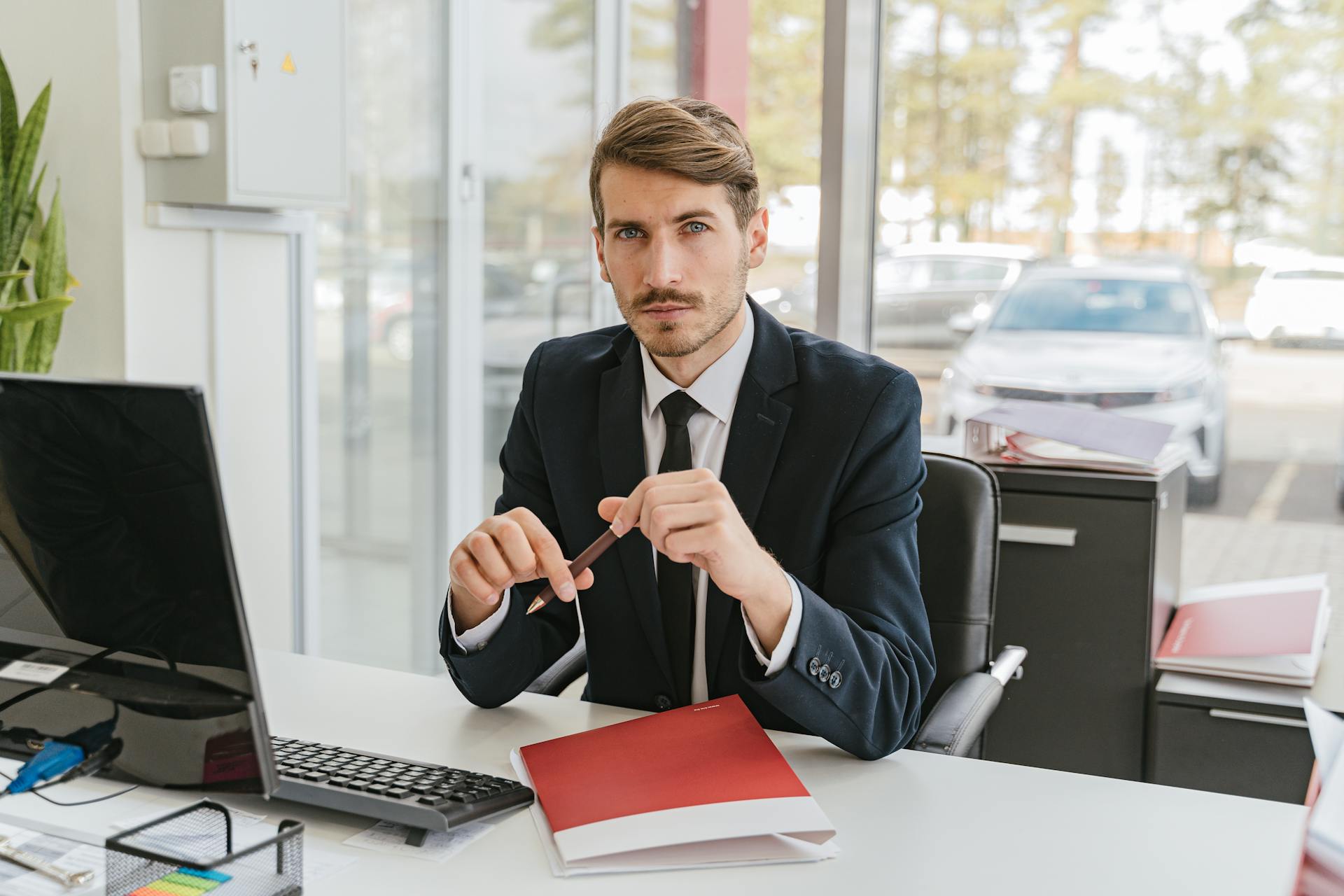 Business professional sitting at a desk with documents in an office environment.