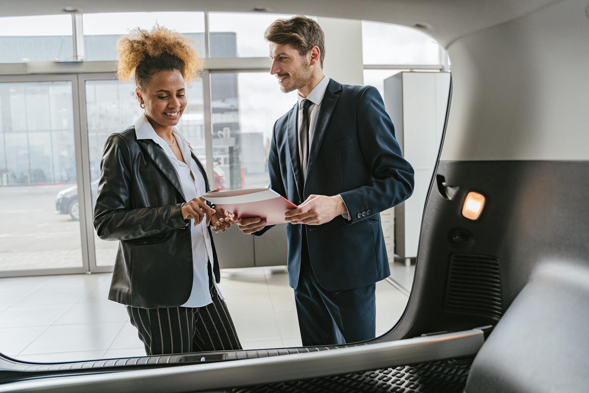 Dealer discussing vehicle options with a client inside a modern car showroom.