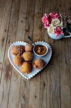 Delicious sugar-coated donuts on a heart-shaped plate with caramel sauce, perfect for dessert lovers.