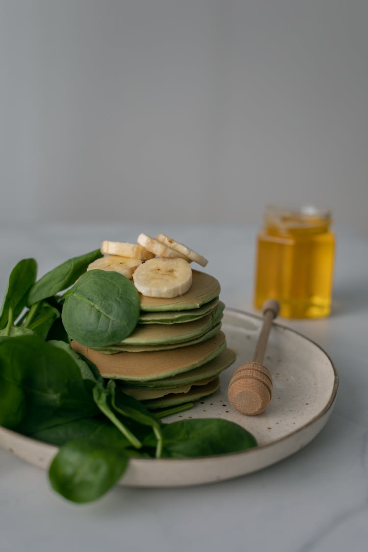 Pancakes With Banana Slices And Spinach Leaves