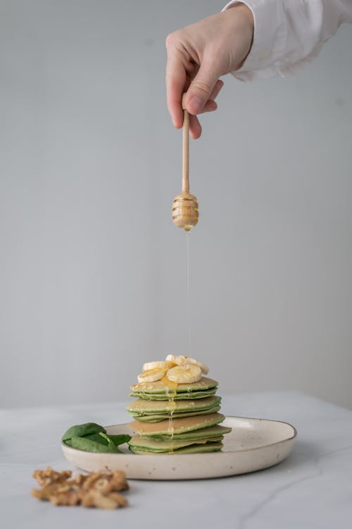 Free A Person Putting Honey on a Stack of Pancakes  Stock Photo