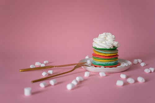 Multicolored pancake with cream served near marshmallow