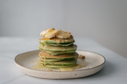 Plate with tasty pancakes topped with fresh sweet honey served on plate on table