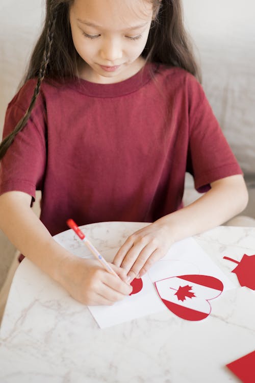 Ein Junges Mädchen Im Roten Hemd, Das Auf Papier Schreibt