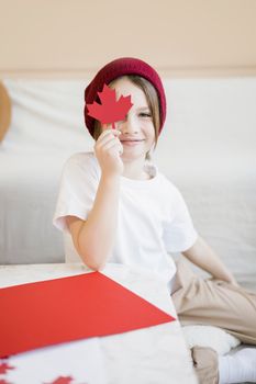 Smiling child with a maple leaf cutout symbolizing Canada, perfect for national pride themes.