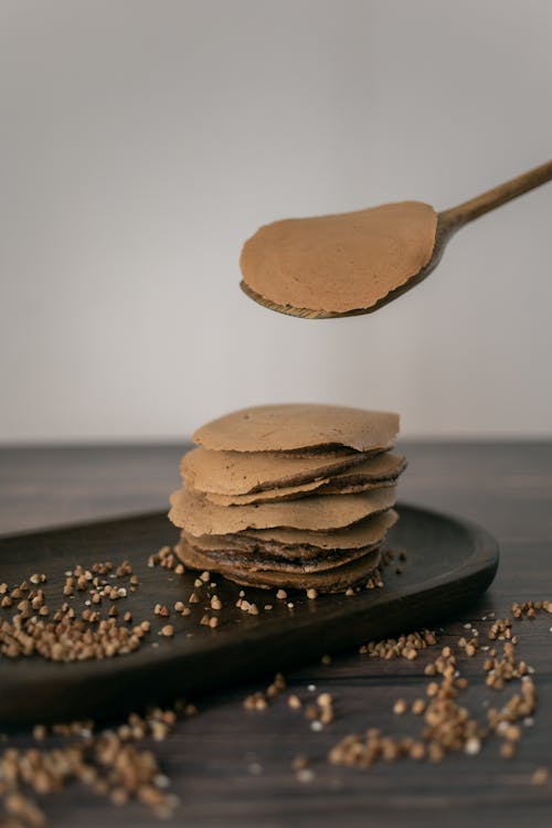 Unrecognizable cook serving buckwheat pancakes on plate