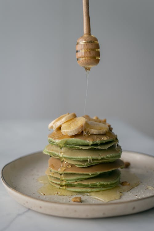 Free Person adding honey on pancakes with wooden dipper Stock Photo