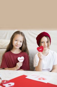 Two kids happily celebrating Canada Day with heart-shaped crafts. Perfect for holiday themes.