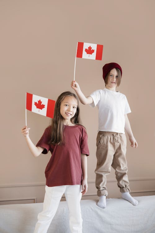 A Boy and a Girl Holding Flags Standing