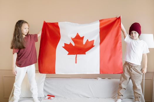 Children proudly display the Canadian flag in a festive indoor setting.