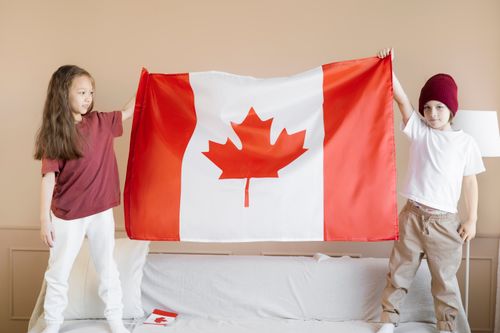 Free Children proudly display the Canadian flag in a festive indoor setting. Stock Photo