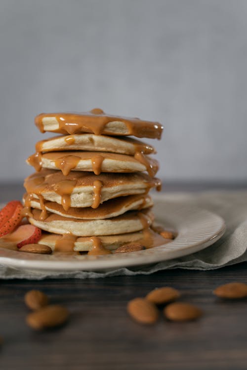 Sweet pancakes with caramel sauce and almonds on plate
