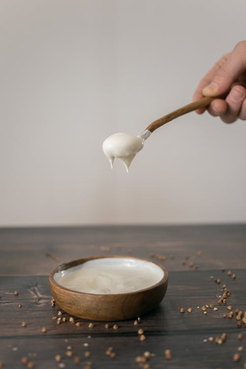 Free Crop person preparing cream in wooden bowl Stock Photo