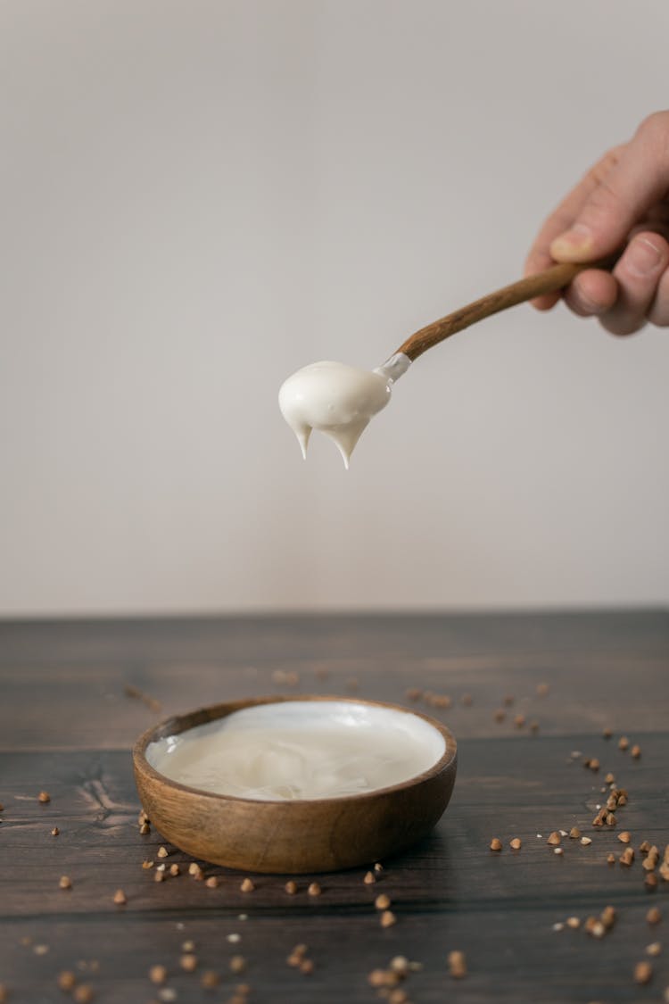 Crop Person Preparing Cream In Wooden Bowl