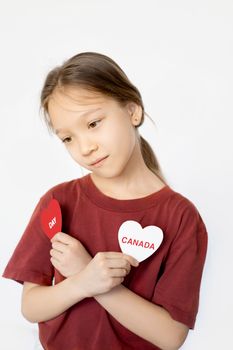Portrait of a young girl holding Canada Day signs, expressing patriotism.
