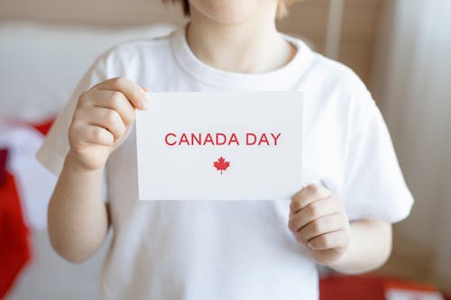 A Child Holding a White Paper with Canada Day Message