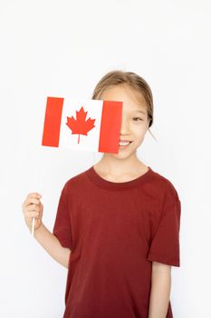 Young girl celebrating Canada Day by holding a Canadian flag with pride.