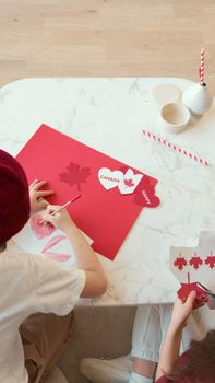 Children crafting Canadian-themed art for Canada Day celebration indoors.