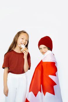 Two smiling children with Canadian flag and ice cream celebrate Canada Day indoors.