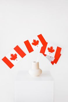 Ceramic vase with Canadian flags on a bright white background symbolizing national pride.