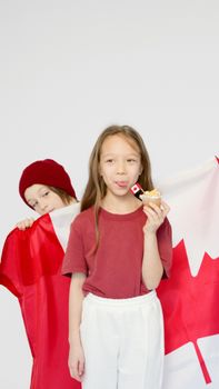 Two children celebrate Canada Day with a flag and cupcake, showcasing national pride and joy.