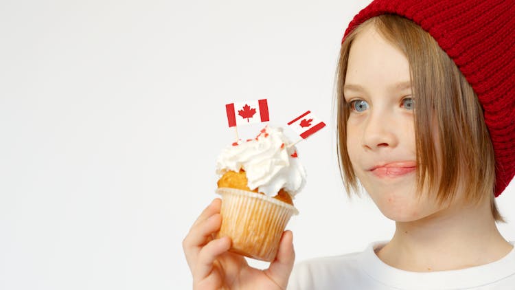 Kid Holding A White Cupcake With Canada Flags