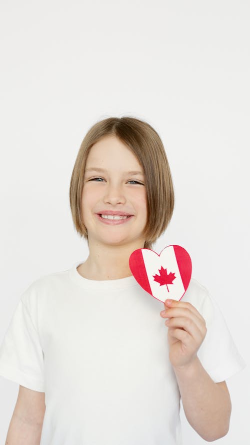 A Kid Holding a Heart Shape with the Canada Flag