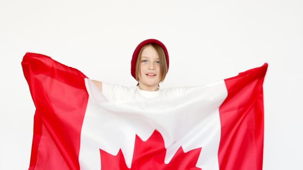 Cheerful child celebrates Canada Day with a Canadian flag indoors, showcasing patriotism.