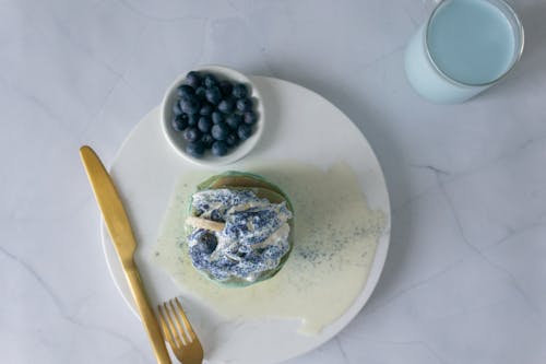 Sweet dessert decorated with white cream near blueberries