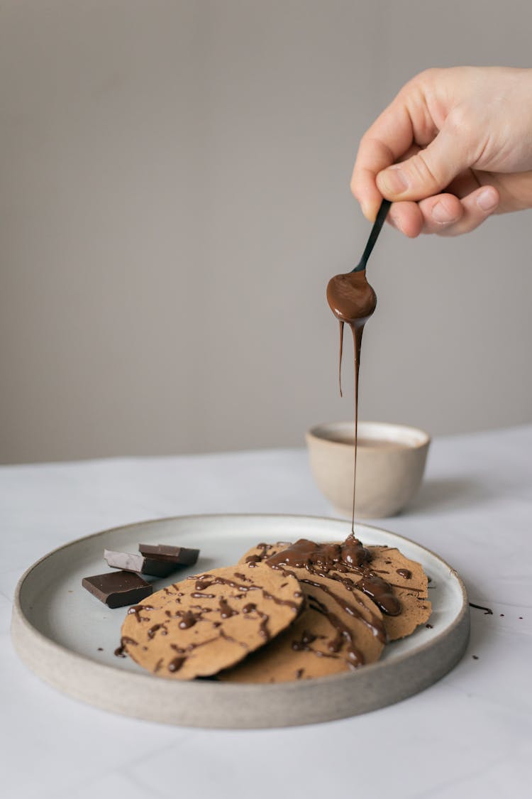 Pancakes Decorated With Chocolate Topping Poured From Spoon