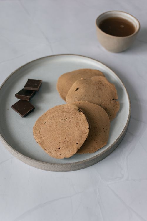 Free Minimalist composition of homemade pancakes with chocolate squares on a ceramic plate. Stock Photo