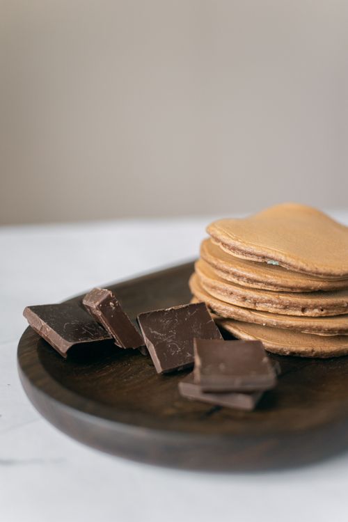 Free Stack of pancakes with dark chocolate on a wooden plate, appetizing and inviting. Stock Photo
