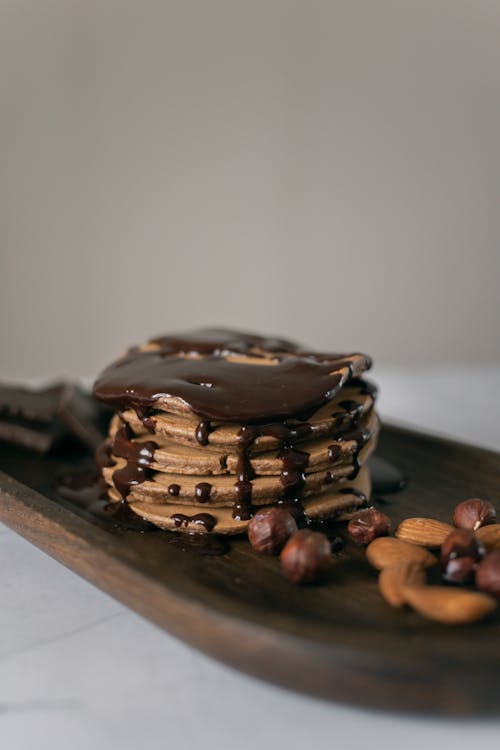Free Delicious pancakes decorated with chocolate and nuts on timber board Stock Photo
