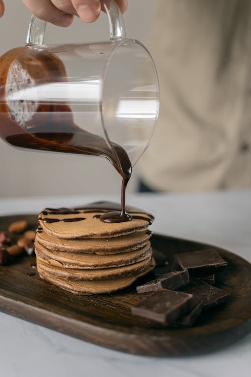 Cook pouring chocolate on fried fresh pancakes