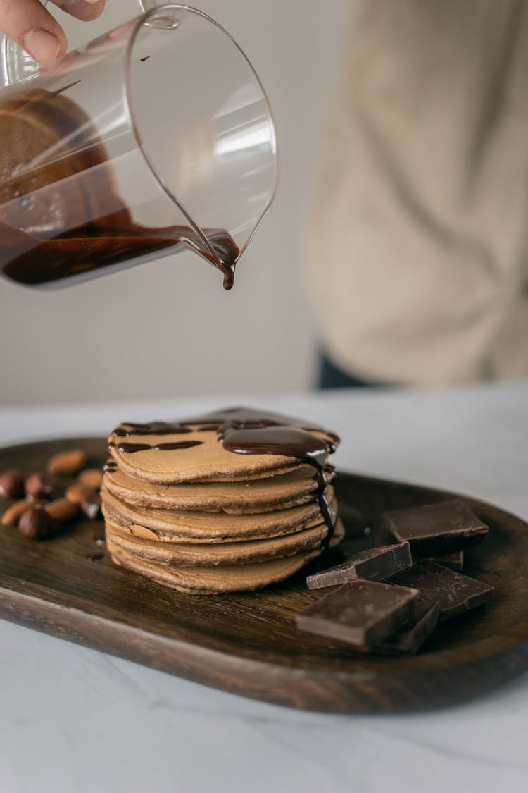 Cook Adding Chocolate Syrup On Pancakes In Kitchen