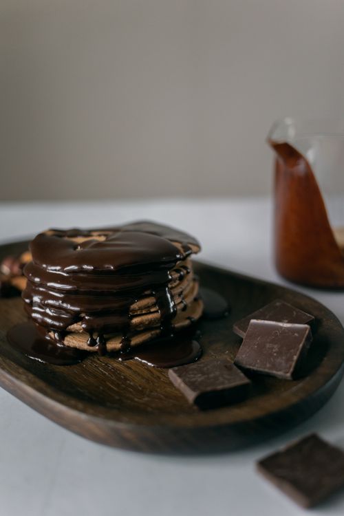 Free Stack of tasty pancakes served on timber board and decorated with chocolate on blurred background Stock Photo