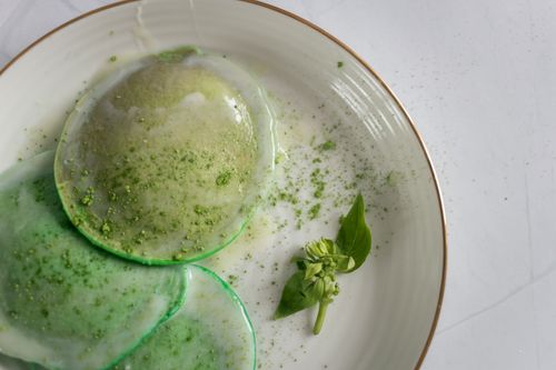 Free From above of delicious poached egg decorated with green seasoning and herb with leaves on white plate on table Stock Photo